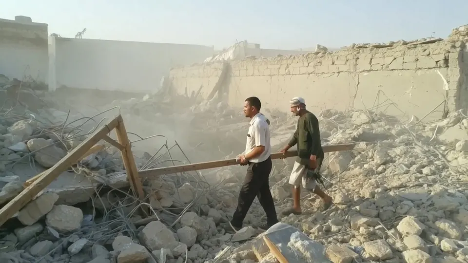 Reddingswerkers lopen door het puin van een gevangenis in Hazm na een luchtaanval
