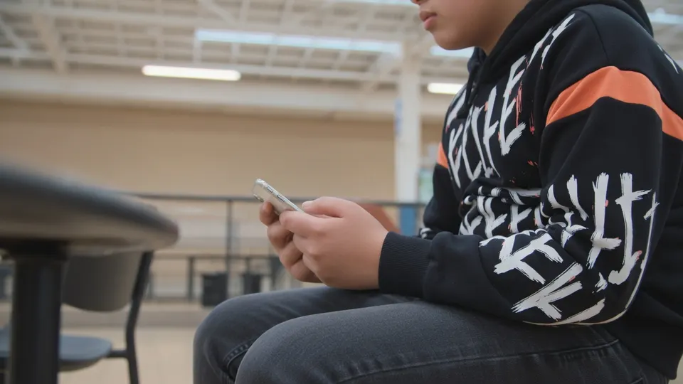 Jongere kijkt op een telefoon, terwijl het kabinet een Europese leeftijdsgrens voor sociale media steunt