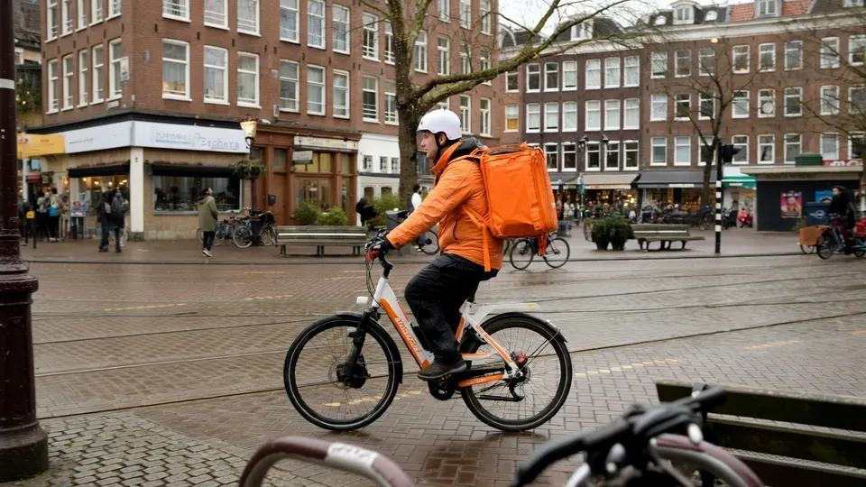 Bezorger van Thuisbezorgd fietst door een winkelstraat