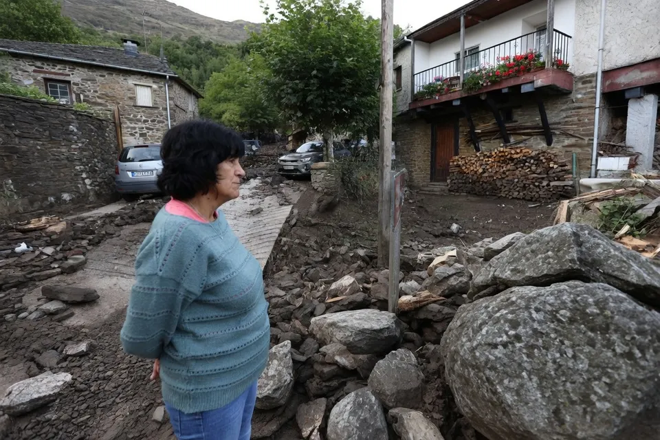 Een vrouw staat tussen rotsblokken en puin na zware regenval in oostelijk Spanje