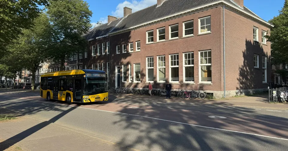 Een bus van Transdev rijdt langs een schoolgebouw in Utrecht