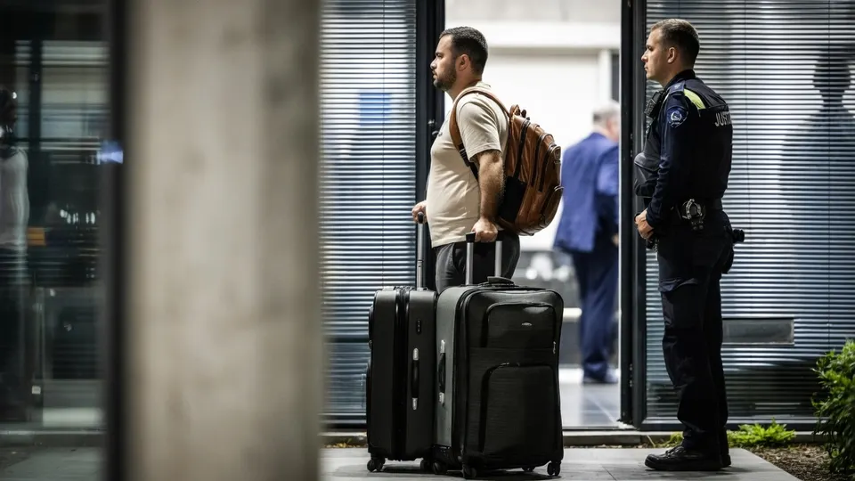 Man met koffers bij een politiebureau