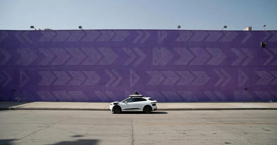 Een zelfrijdende Waymo-auto rijdt langs een muur