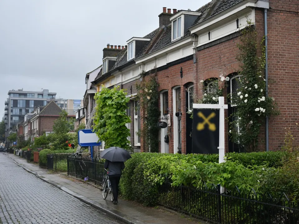 Een bord met een doorgestreept huis bij een woning in een straat