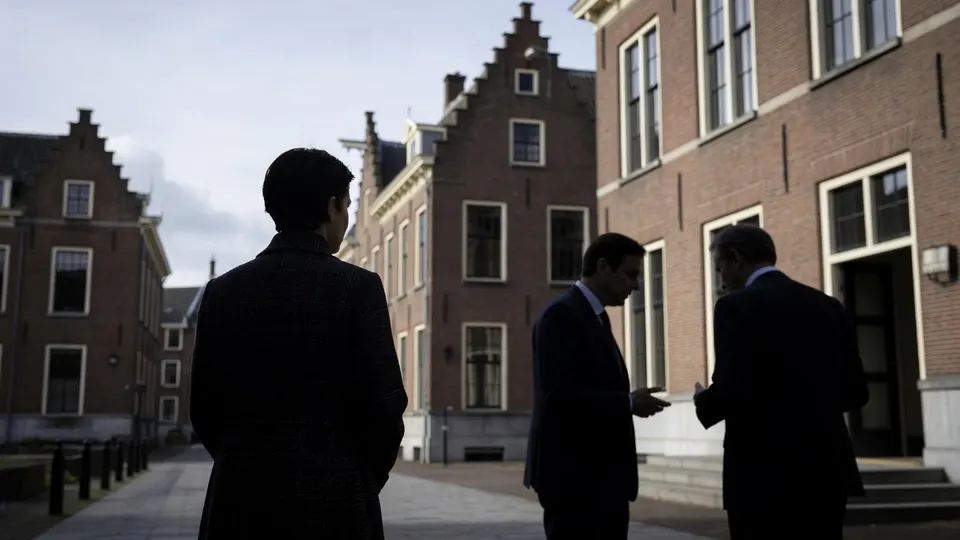 Drie mannen praten buiten een gebouw