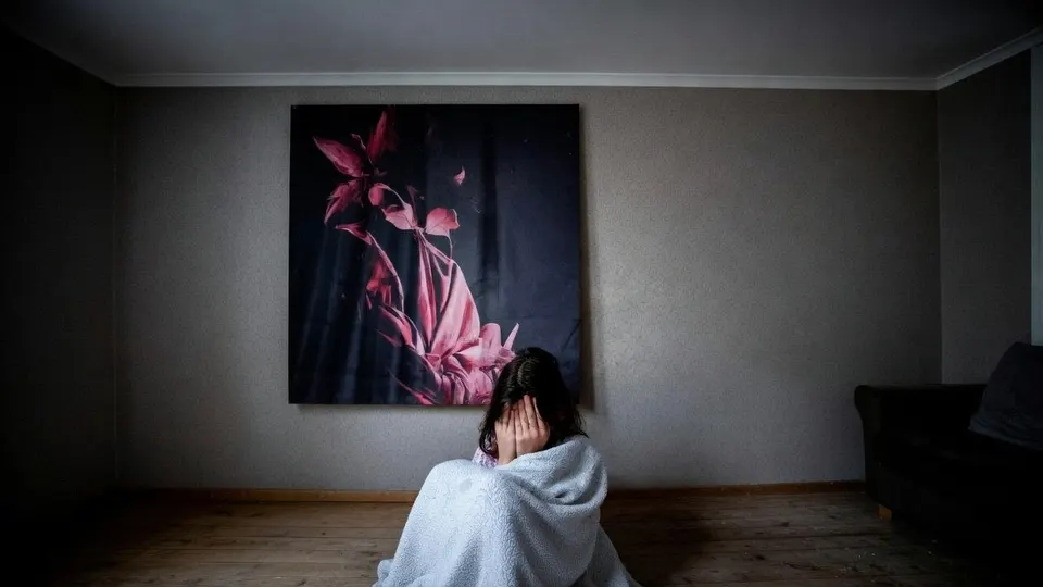Kind zit alleen en gehuld in een deken in een woonkamer