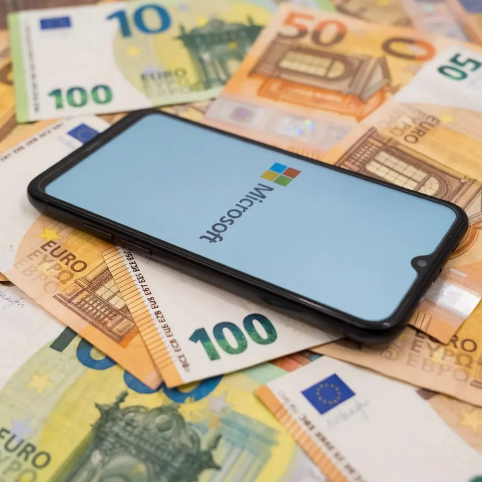 Een smartphone met het Microsoft-logo ligt op euromunten en -biljetten