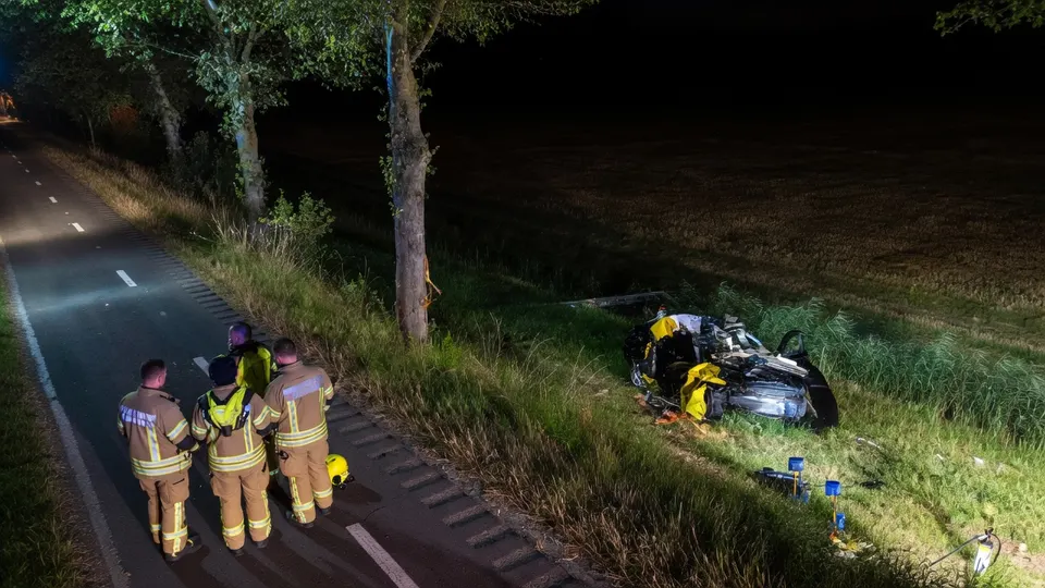 Hulpverleners bij een auto die na een eenzijdig ongeluk in een sloot langs de Westdijk is beland