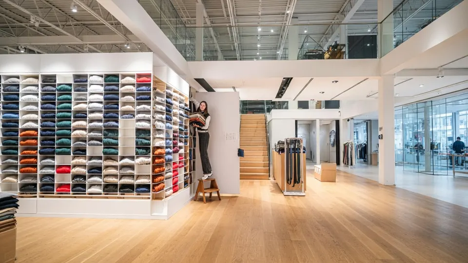 In een kledingwinkel liggen truien en andere kledingstukken uitgestald
