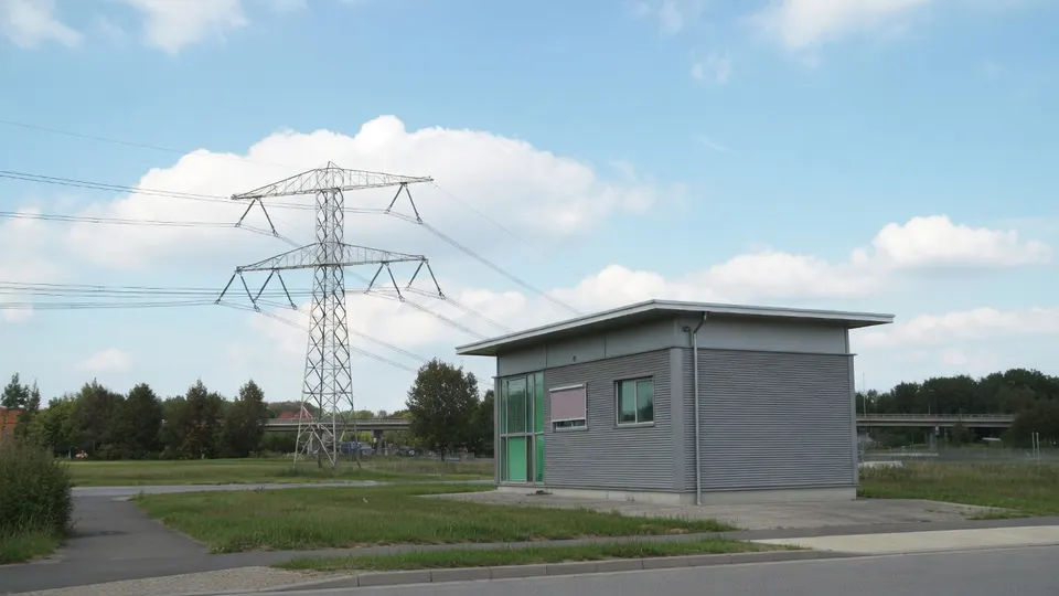 Een elektriciteitsmast en een klein gebouw van een netbeheerder