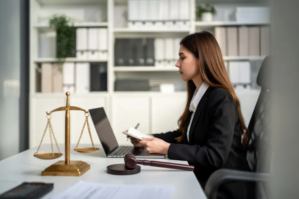 Illustratie van een advocaat aan het werk met een weegschaal en hamer op haar bureau