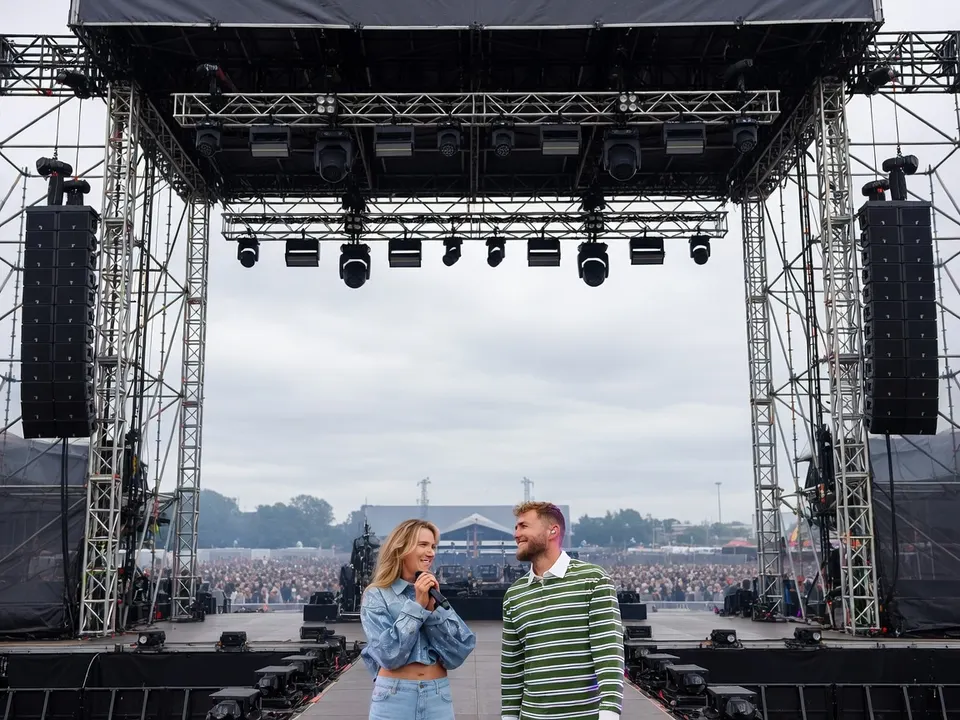 Suzan en Freek staan samen op een podium voor een groot publiek