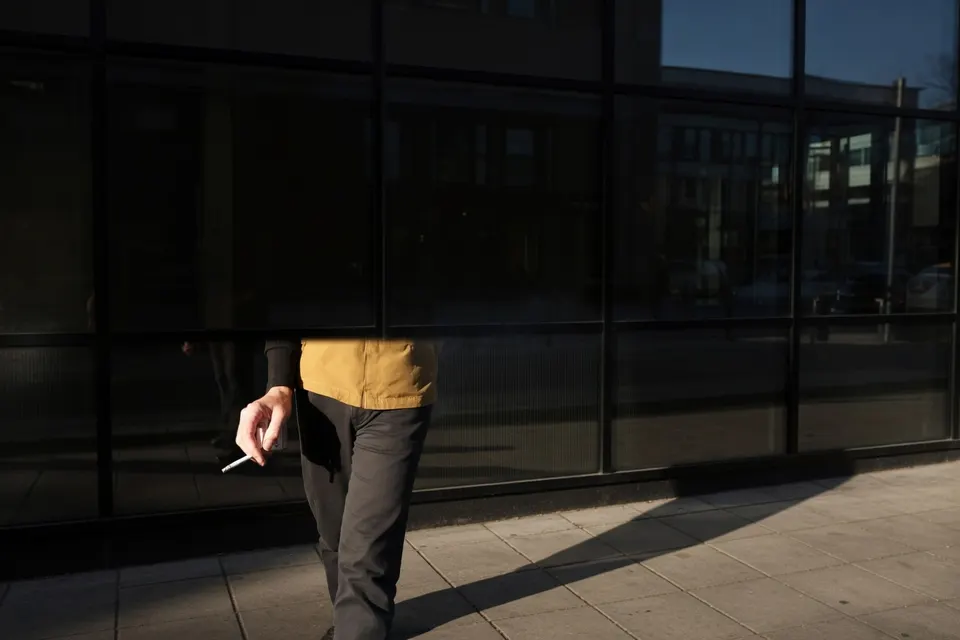 Roker loopt met een brandende sigaret langs een kantoorgebouw