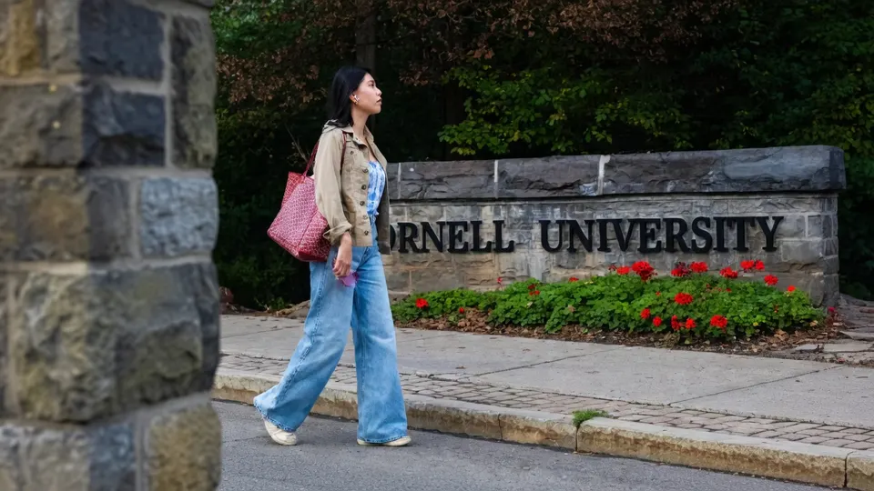 Student loopt langs een bord van Cornell University in Ithaca, New York