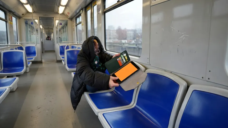 Een persoon gebruikt een smartphone in een trein, ter illustratie bij het nieuws over bankhelpdeskfraude