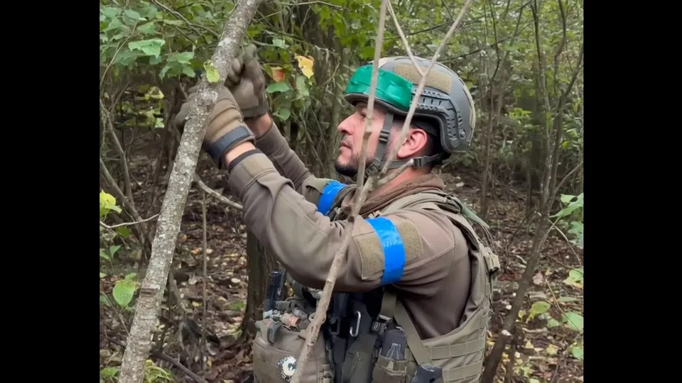 Gewapende man in camouflagekleding en met helm in een bos