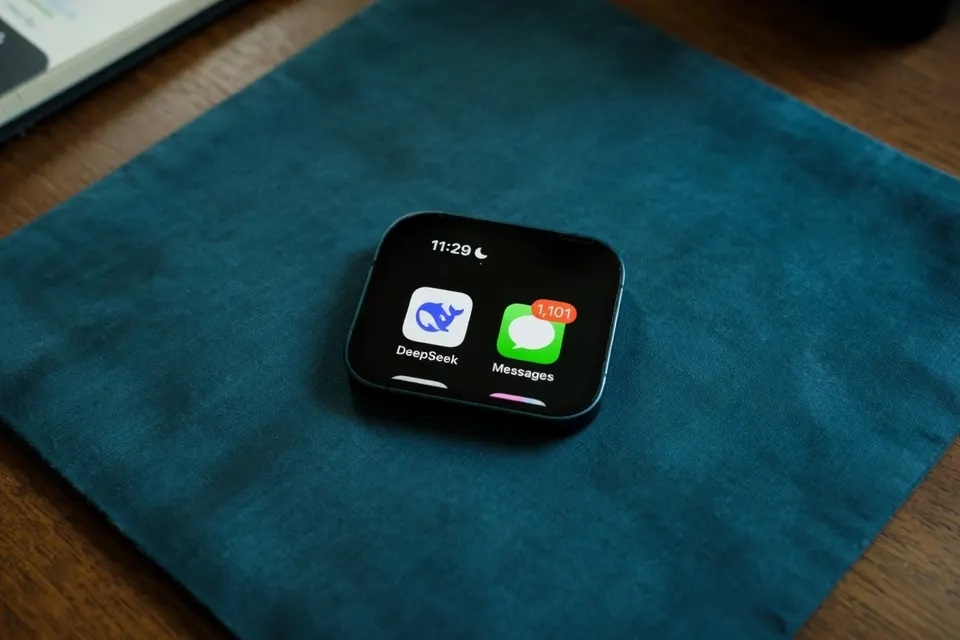 Smartphone met apps van DeepSeek en Berichten op een tafel