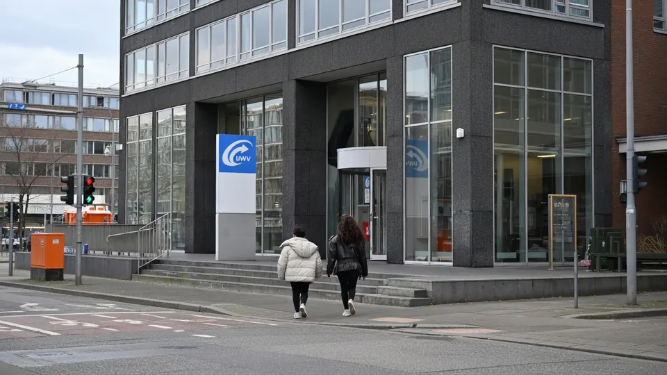 Twee mensen lopen langs een UWV-kantoor