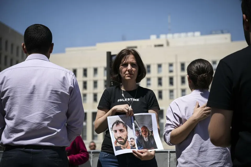 Een vrouw toont foto's van slachtoffers tijdens een bijeenkomst van Palestijnen