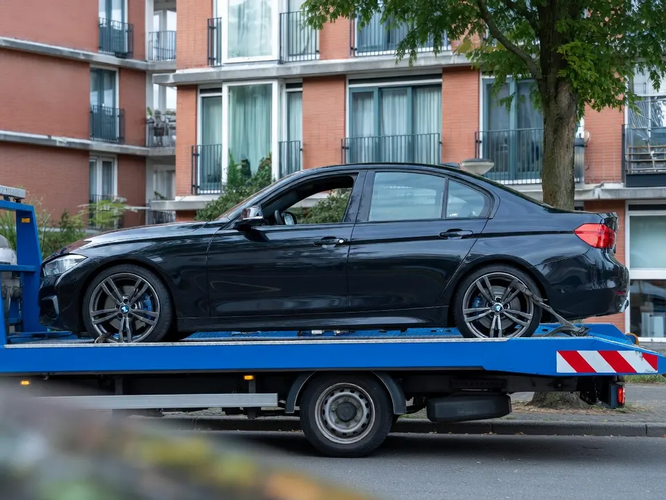 BMW die na een politieachtervolging in Amsterdam-Osdorp crashte, wordt op een bergingswagen afgevoerd