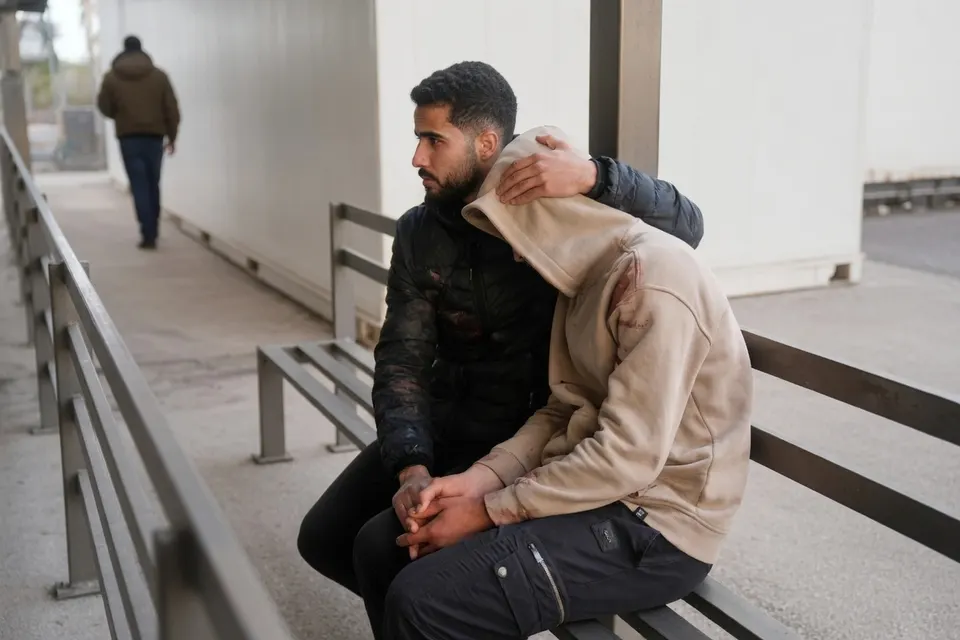 Twee mannen zitten naast elkaar op een bankje, van wie één een arm om de ander heeft geslagen