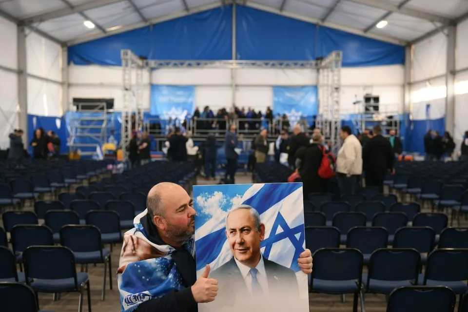 Man houdt een poster van Benjamin Netanyahu vast tijdens een verkiezingsbijeenkomst van Likoed