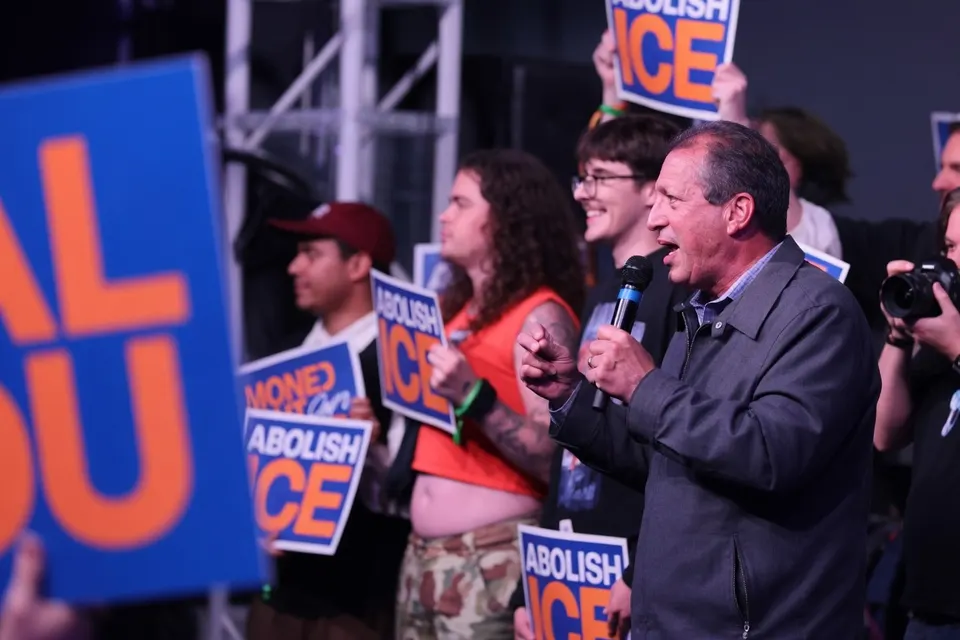 Een spreker voert het woord tijdens een demonstratie waar mensen protestborden tegen ICE vasthouden