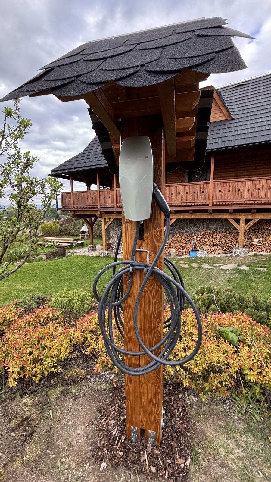 Nabíjacia stanica Tesla Wall Connector na drevenom stĺpe pri chate