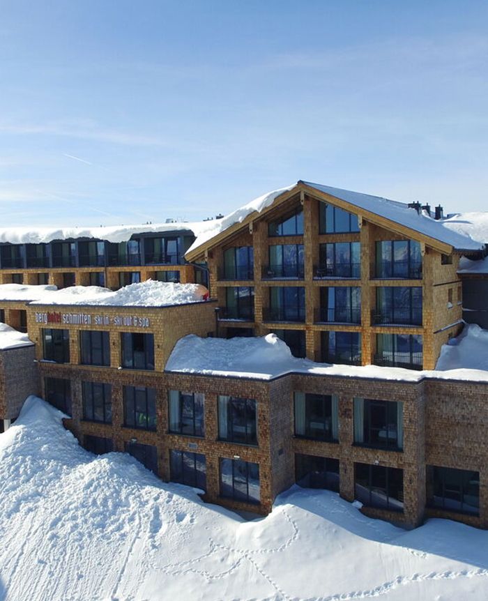 Mehrstöckiges Hotelgebäude aus Holz mit großen Fenstern, umgeben von Schnee im Winter.