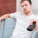 A man has his hand on the remote control