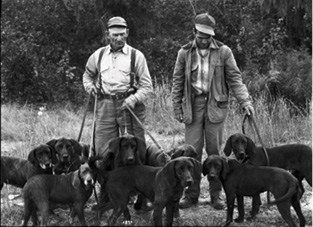 The Plott | A Hound of a Different Color Two unidentified members of the Plott family with their hounds before a hunt.