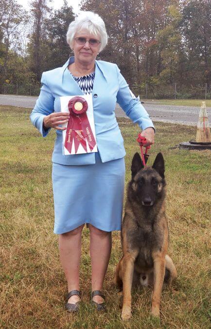 Susan Legg standing with her dog Broadcreek Belgian Malinois