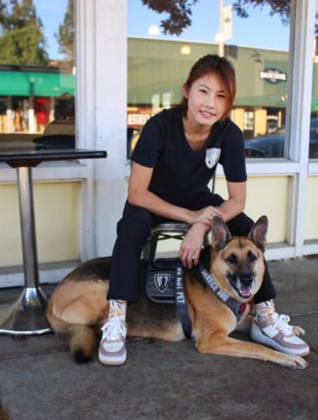 Asia Duhamel sitting on a chair with her Service Dog, German Shepherd known as "Lotus"