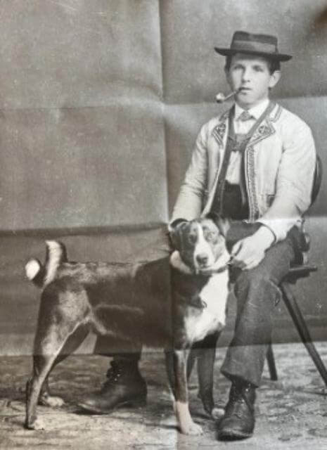 The Alpine herdsman sits with his Appenzellerherding companion
