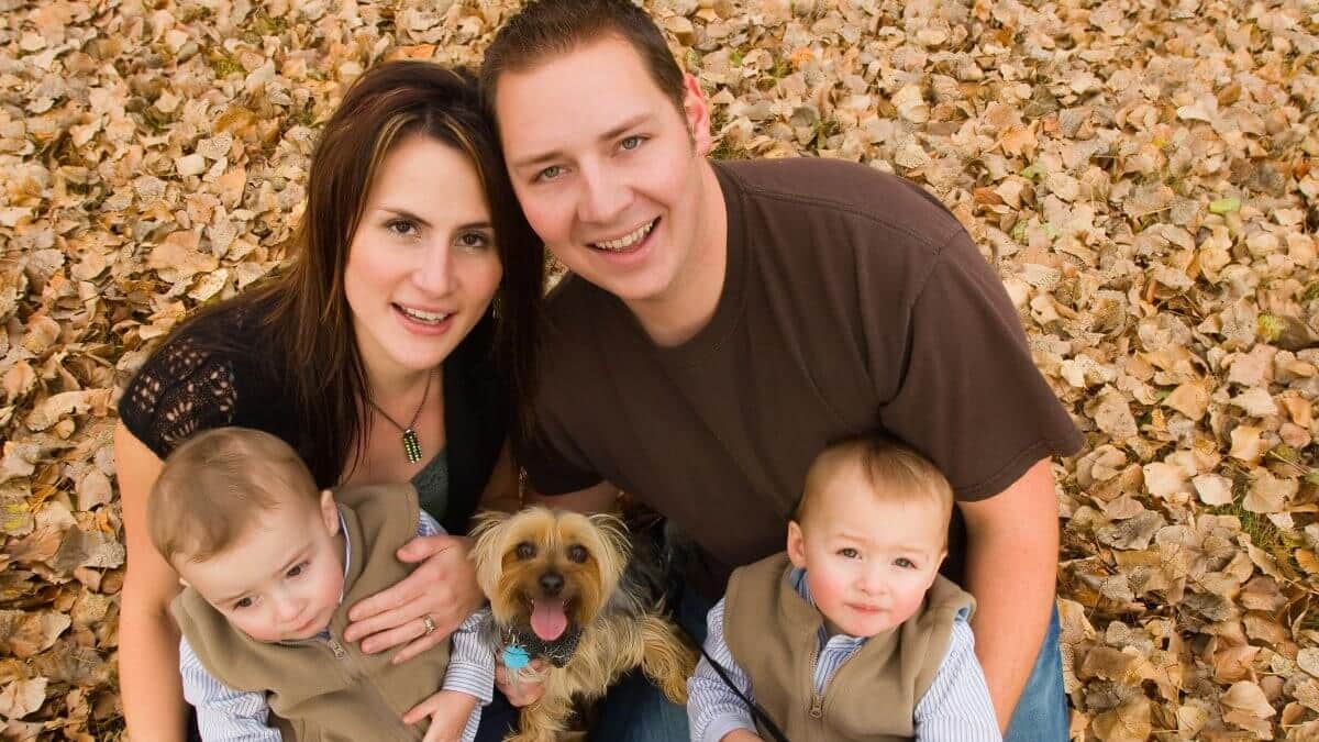 Family in autumn. Young family with twin boys and pet dog in autumn leaves