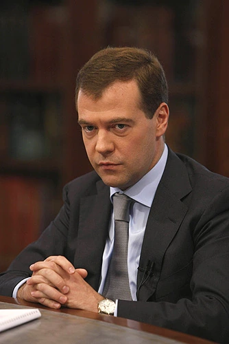 Dmitry Medvedev seated at a table in a formal suit and tie during an interview or meeting