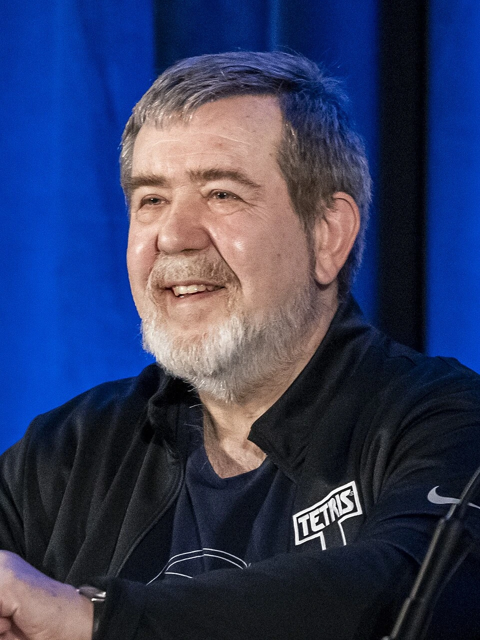 Alexey Pajitnov smiling at an event, wearing a dark jacket with a Tetris logo