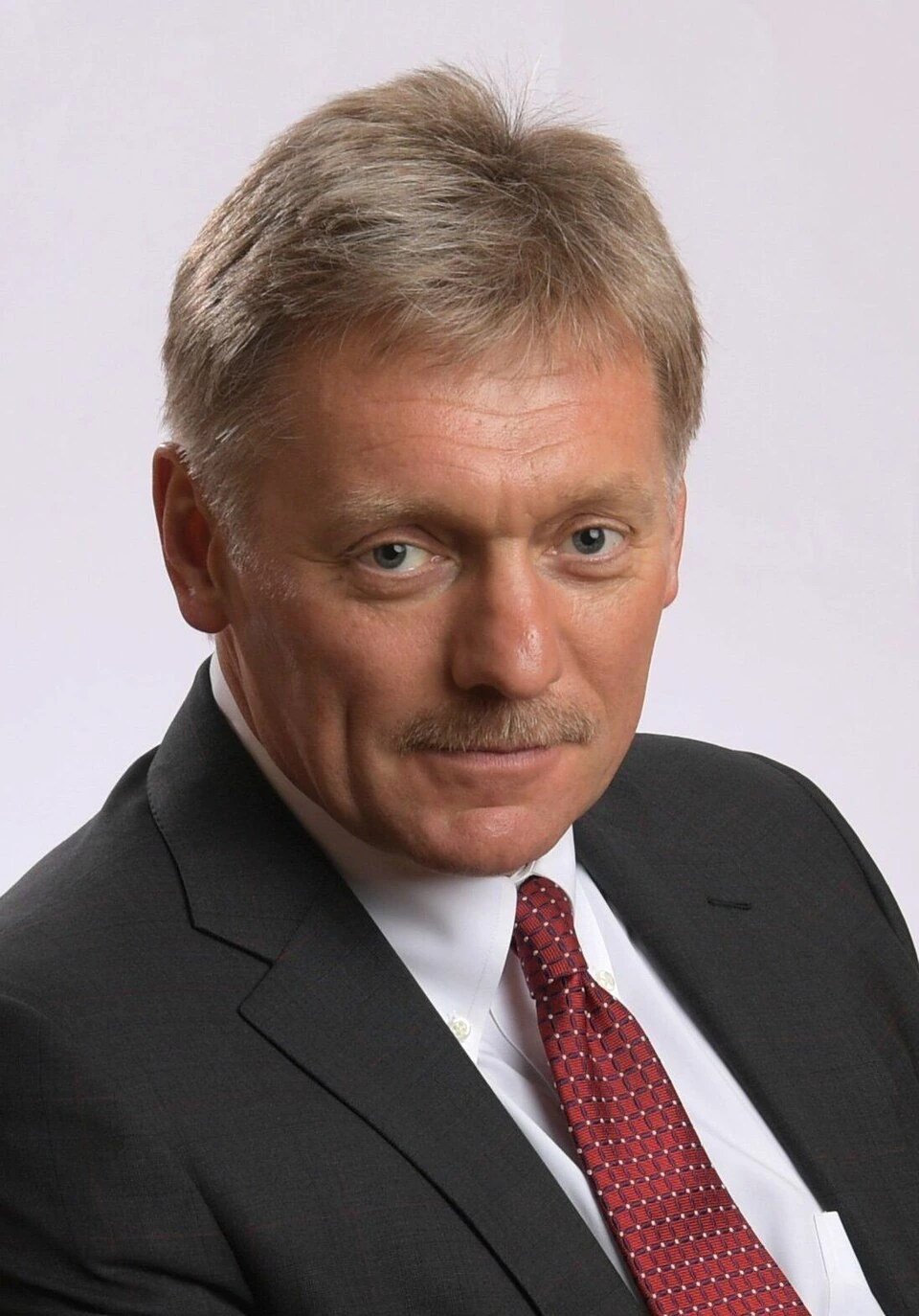 Portrait of Dmitry Peskov in a suit and tie.