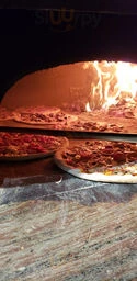 A dimly lit restaurant scene with pizzas baking in a wood-fired oven at The Fix Resto Bar & Patio Toronto