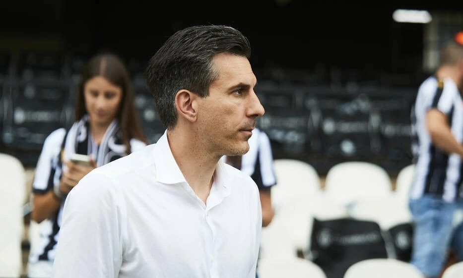 Haralabos Voulgaris in profile at a football match, wearing a white shirt