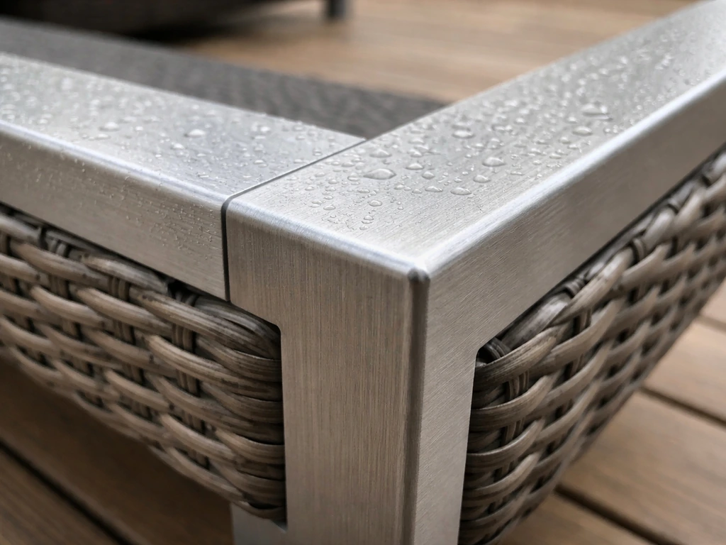 Close-up of an aluminum frame with resin wicker and water beading, suggesting weather durability.