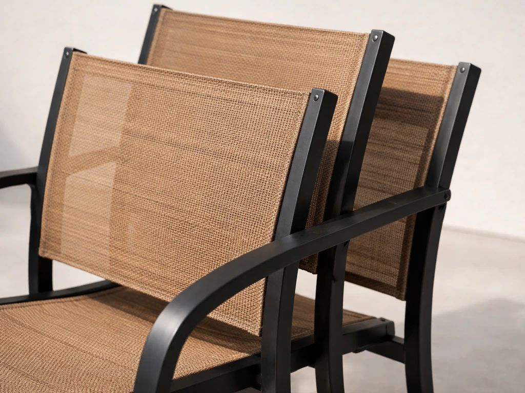 Close-up of matte black and tan sling stackable dining chairs showing fabric texture and frame details.