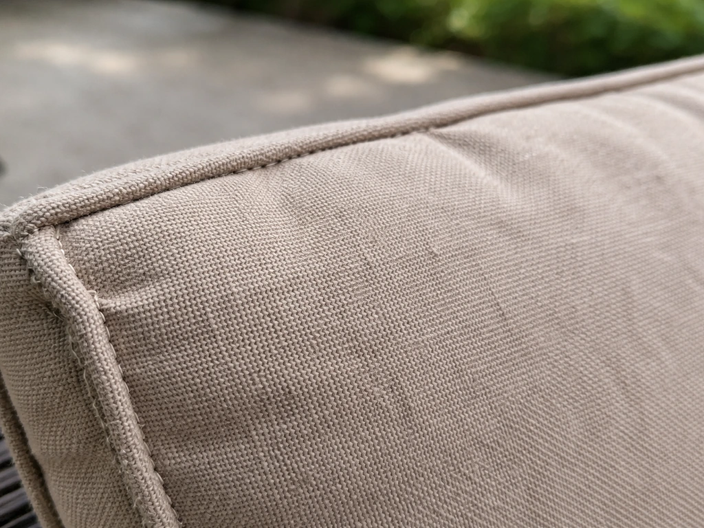 Close-up of beige polyester outdoor cushions showing visible fabric weave and mild sun-fade wear