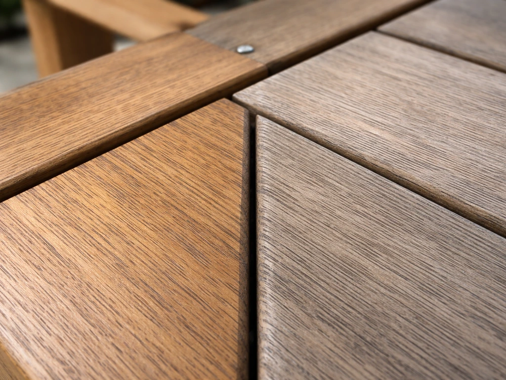 Close-up of outdoor teak furniture showing natural finish and grey-washed aged grain textures side by side.