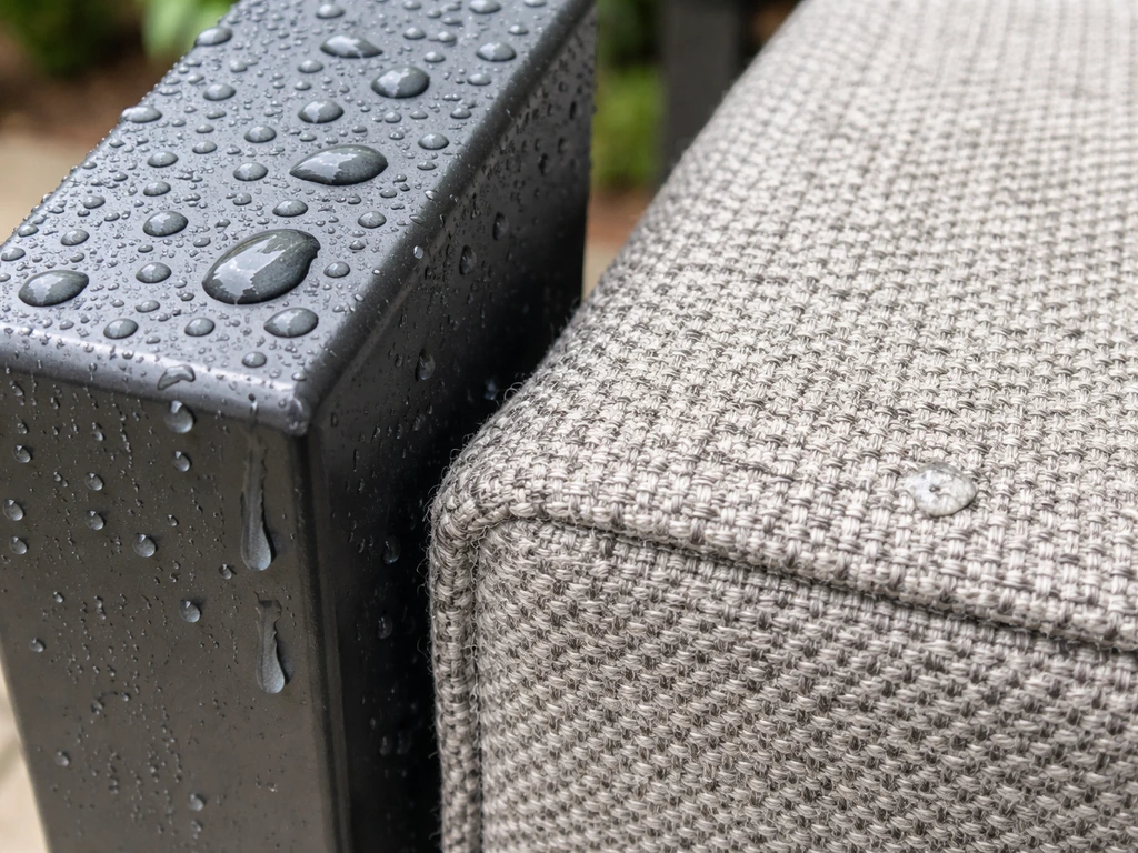 Water beads on a powder-coated aluminum frame alongside damp outdoor olefin fabric texture.
