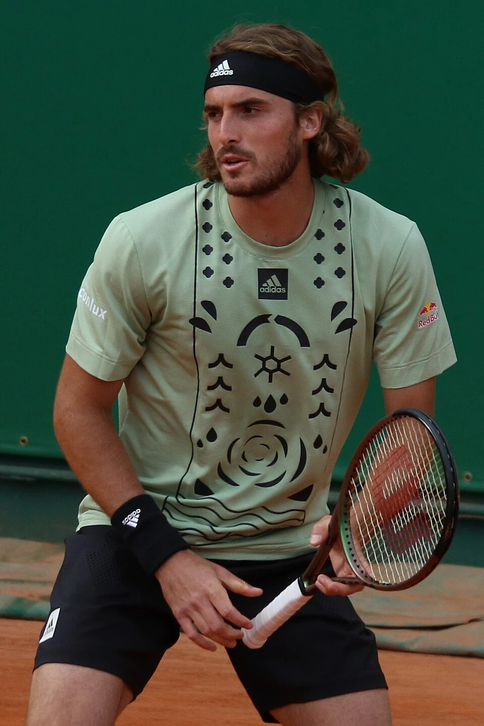 Stefanos Tsitsipas holding a tennis racket on clay court
