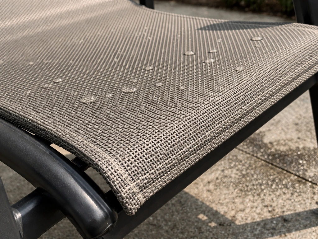 Close-up of taut woven sling-mesh fabric with water droplets beading, suggesting breathable quick-dry durability.