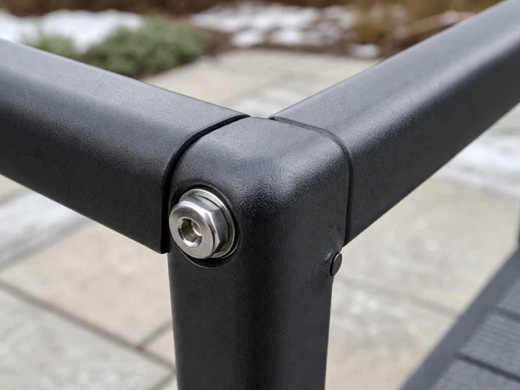 Close-up of powder-coated aluminum patio furniture joint with stainless hardware in winter light.