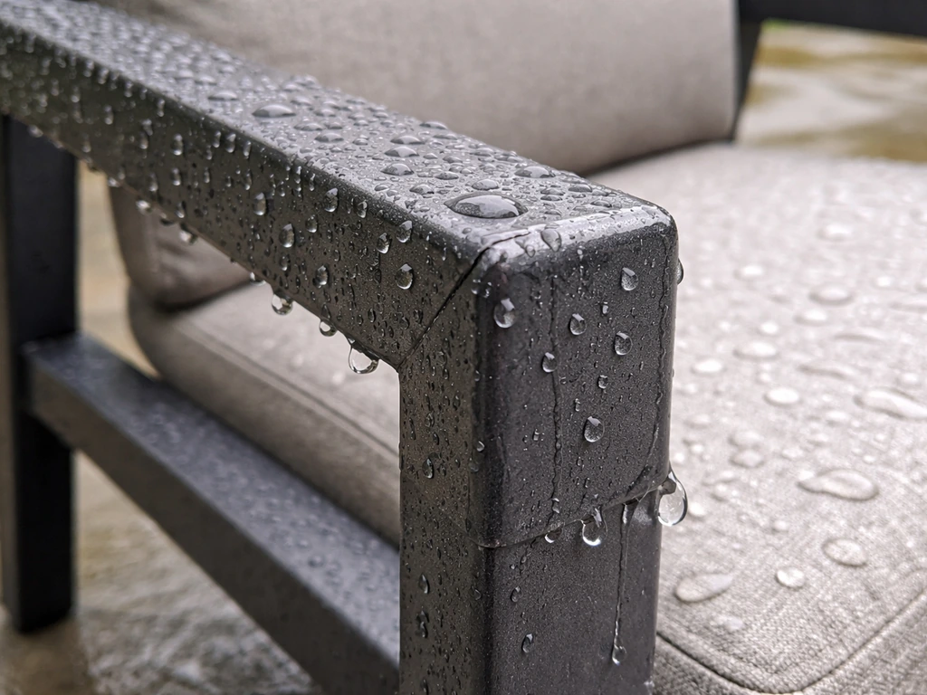 Close-up of a wet powder-coated aluminum chair frame with water beading and droplets draining from joints.