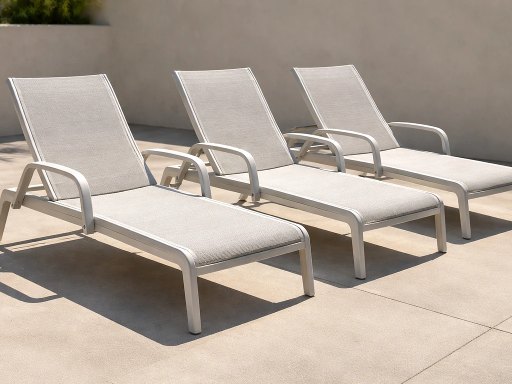 Direct-sun view of powder-coated aluminum chaise lounges with UV-facing sling cushions on a patio